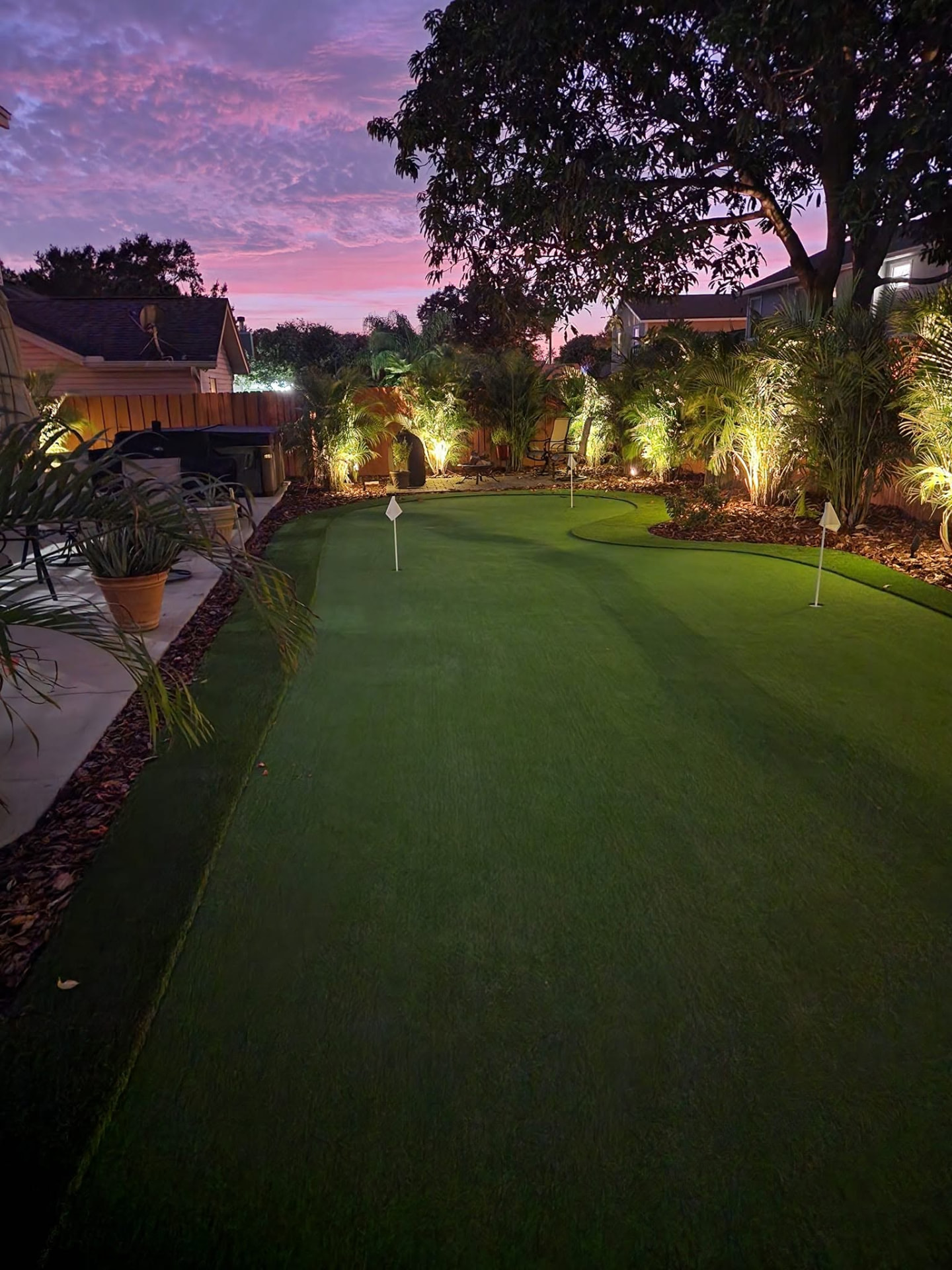 Backyard putting green with landscape lighting at sunset