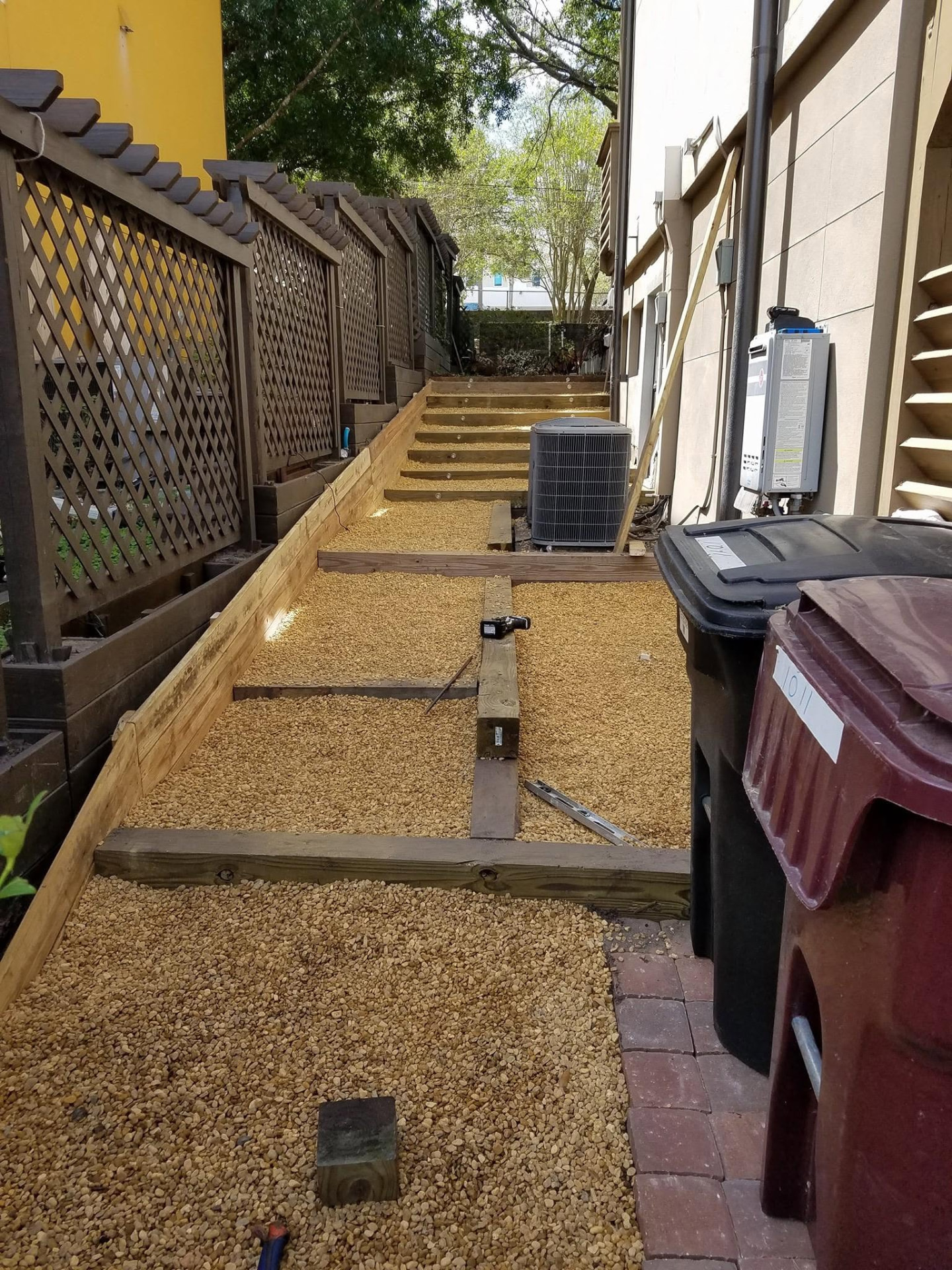 Gravel side-yard walkway with wooden steps and lattice privacy fence